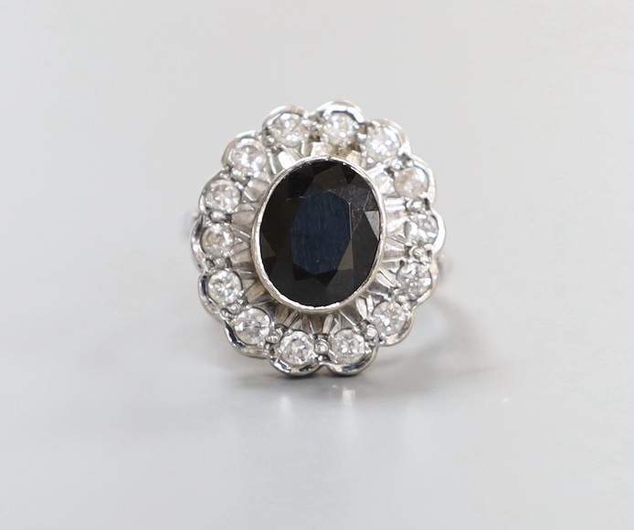 A modern 18ct white gold, sapphire and diamond set oval cluster ring, size L, gross weight 7.6 grams.